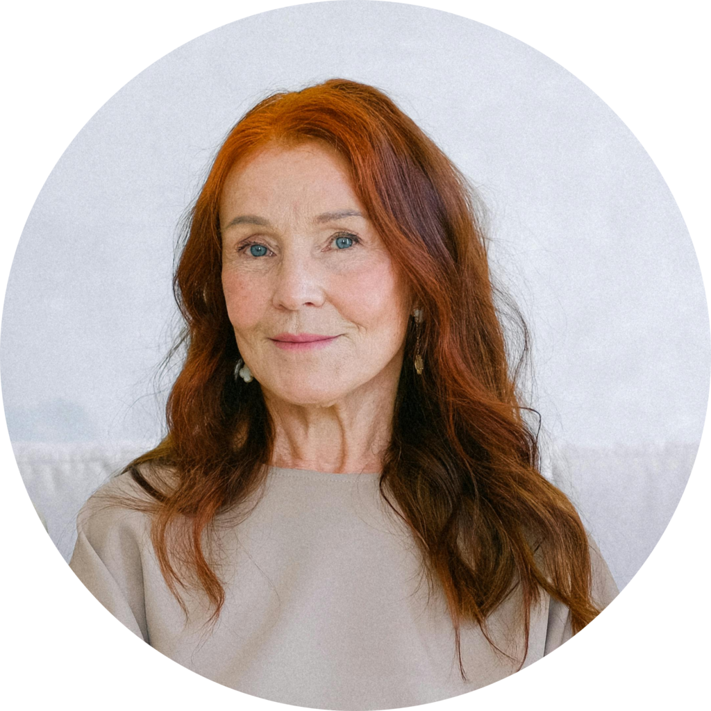 A person with wavy, reddish-brown hair wearing a beige top, set against a soft, light background in a circular frame.